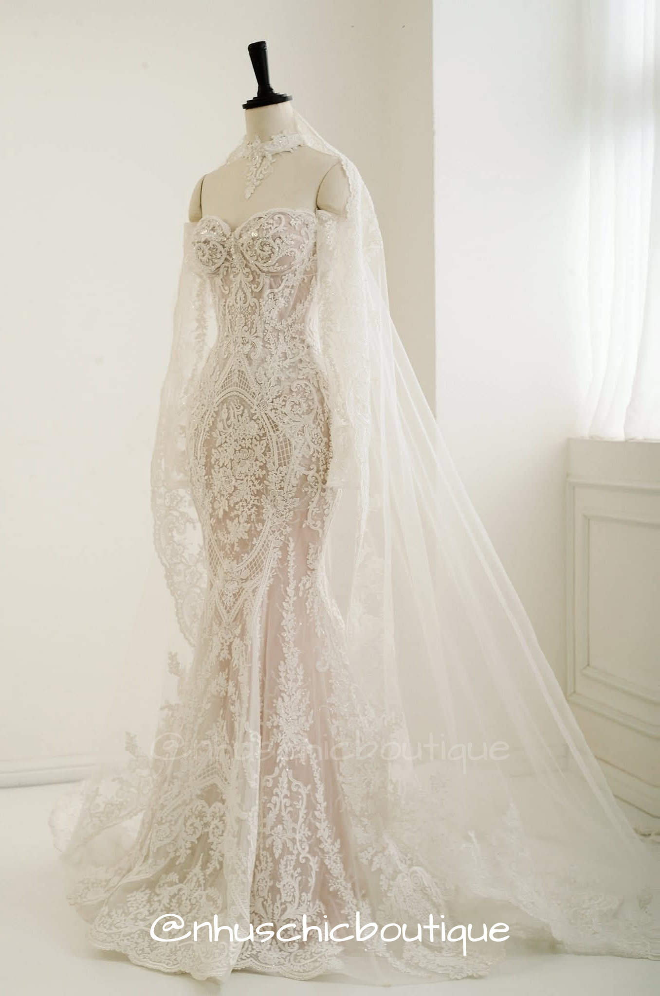 Side view of the Nhuschicboutique convertible bridal gown styled as a lace mermaid dress with a matching lace high-neck collar cape and a long sheer embroidered cathedral veil.