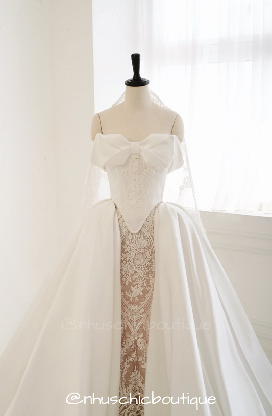 4-in-1 convertible wedding dress by Nhuschicboutique featuring a structured white satin ball gown overskirt with a large statement bow bodice over an intricate lace underskirt.