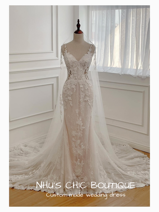 Elegant lace wedding dress on a mannequin in a room with white walls and curtains.